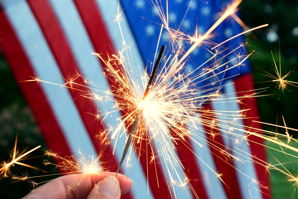 American flag as backdrop for a lighted sparkler