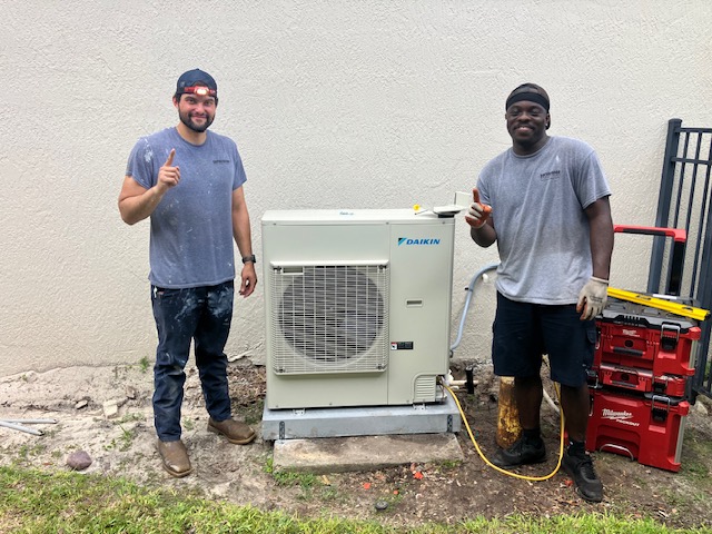 ServiceOne techs smiling while installing a Daikin FIT system.