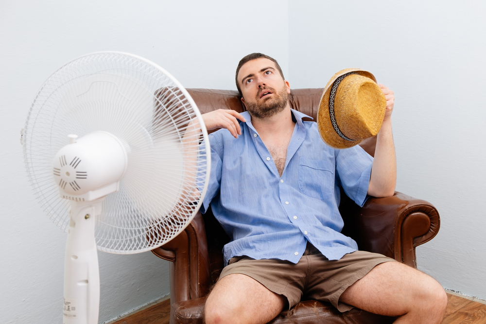 hot man in front of fan who needs a heat pump to stay cool in Central Florida!