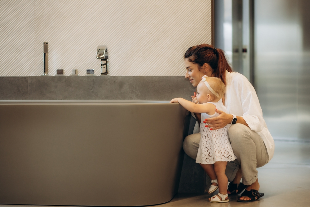 mother and girl toddler looking into a bathtub